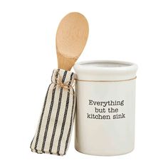 a wooden spoon sitting next to a white container with a black and white striped napkin