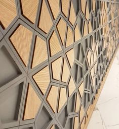 a wall made out of wood and metal with geometric designs on the side, along with marble flooring