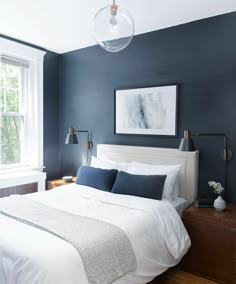 a bedroom with blue walls and white bedding