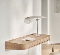 a wooden desk with a lamp on it and a glass in front of the table