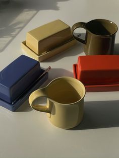 there are many different colored cups and containers on the table, including one with a spoon