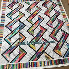 a quilted table topper with colorful strips on it