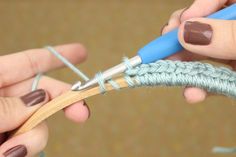 two hands are crocheting together with yarn and scissors to make a knitted bracelet