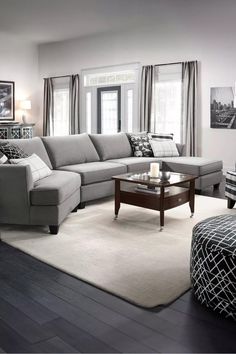 a living room with gray couches and white rugs on the hardwood flooring