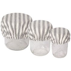 three glass cups with black and white striped covers on top of each cup, one is empty