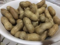 a white bowl filled with peanuts sitting on top of a table