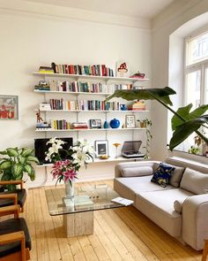 a living room filled with lots of furniture and bookshelves next to a window