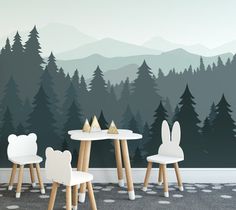 two white chairs sitting at a table in front of a forest wall mural