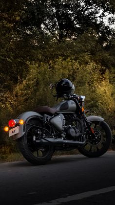 the motorcycle is parked on the side of the road near some bushes and trees in the background