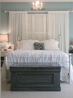 a white bed sitting in a bedroom under a chandelier