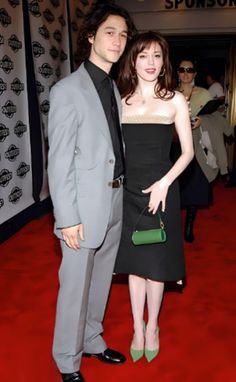 a man in a suit and tie standing next to a woman on a red carpet