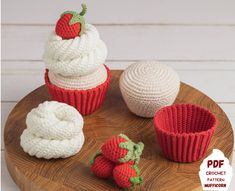 three crocheted cupcakes and two strawberries on a wooden platter