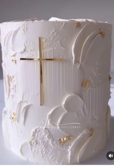 a white cake with gold decorations and a cross on top