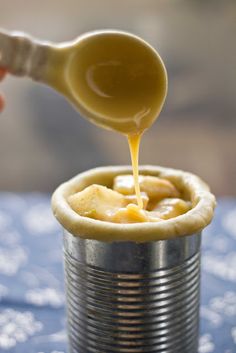 a person pouring caramel sauce on top of an apple pie in a tin can