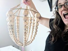 a woman holding up a wooden bead mobile