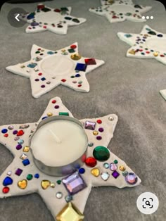 a white candle sitting on top of a table covered in glass stars and other decorations