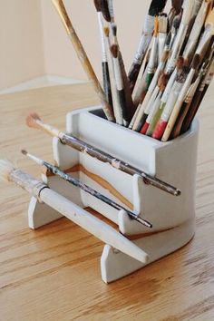 a cup filled with paint brushes on top of a wooden table