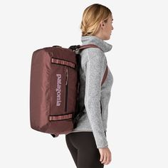 a woman carrying a large brown backpack on her back with the words patagon printed on it