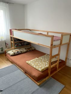 a bunk bed sitting on top of a hard wood floor next to a rug and window