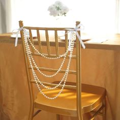 a chair with pearls tied to it and a flower vase on the back of it