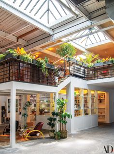 the inside of a building with plants and books on the balconies above it