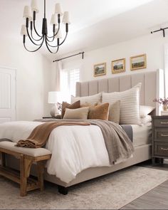 a bedroom with a bed, dresser and chandelier