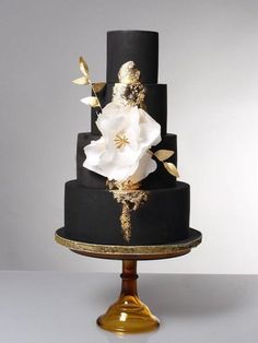 a black and gold wedding cake with white flowers