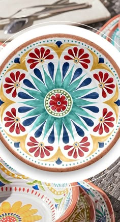 colorful plates are stacked on top of each other in different colors and designs, including flowers