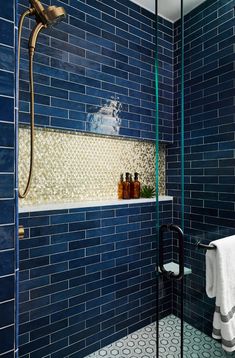 a blue tiled bathroom with glass shower doors