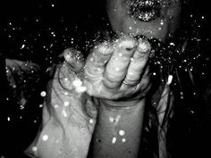 a black and white photo of someone holding their hands in the air with snow all over them