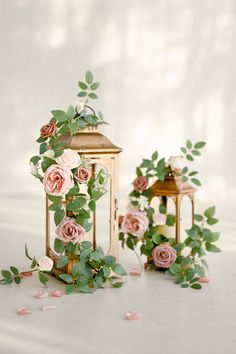 some pink flowers and green leaves on a white table with a small light fixture in the background