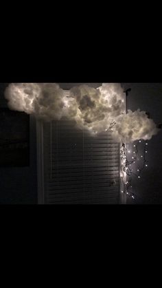 a cloud is floating in the air above a window with lights hanging from it's sides