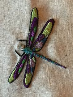 an embroidered dragonfly sitting on top of a white cloth