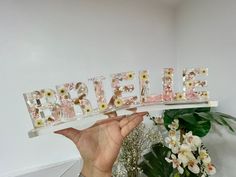 a person holding up the word bride spelled with flowers