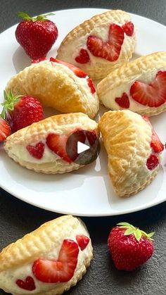 strawberry cream filled pastries on a white plate with fresh strawberries around the edges