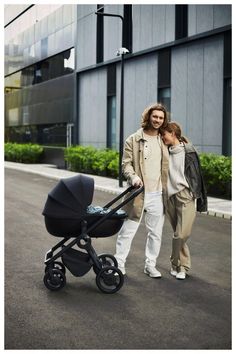 a man and woman walking down the street with a baby stroller in front of them