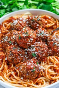 spaghetti and meatballs in a white bowl with parmesan cheese on the side