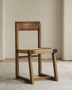 a wooden chair sitting on top of a white floor next to a wall in an empty room