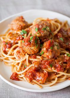 spaghetti with meatballs and sauce in a white bowl