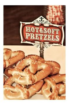 some pretzels are piled on top of each other in front of a sign that says hot and soft pretzels