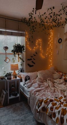 an unmade bed sitting next to a window in a room with lights on the wall