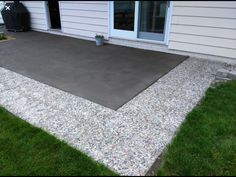 a concrete patio in front of a house with grass growing on the ground and an open door