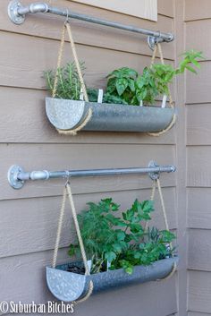 two hanging planters with plants in them on the side of a house's wall