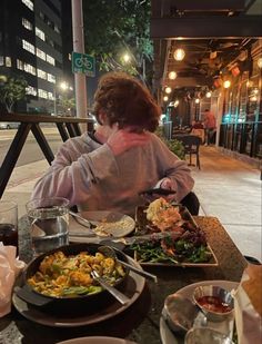 a woman sitting at a table covered in food