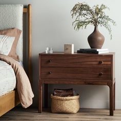 a bedroom with a bed, nightstand and plant on the end table next to it