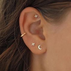 a woman's ear with two small stars and a moon on the middle one