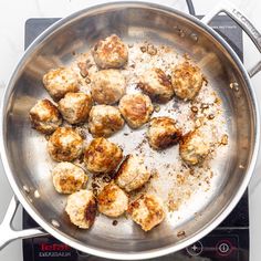 meatballs are being cooked in a pan on the stove top, with seasoning sprinkled around them