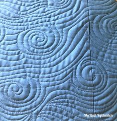 a close up view of a blue quilt with swirls on the back and sides