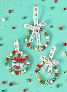 three christmas ornaments with candy and candies around them on a turquoise background, one has a small ornament hanging from it's side