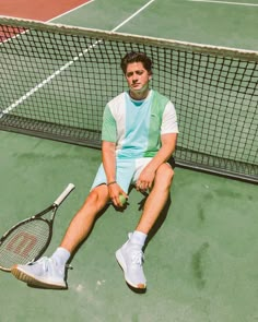 a tennis player sitting on the court with his racquet and ball in hand